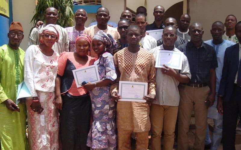Professionnels en formation continue tenant leur attestation, devant l’entrée du CFP-STAT